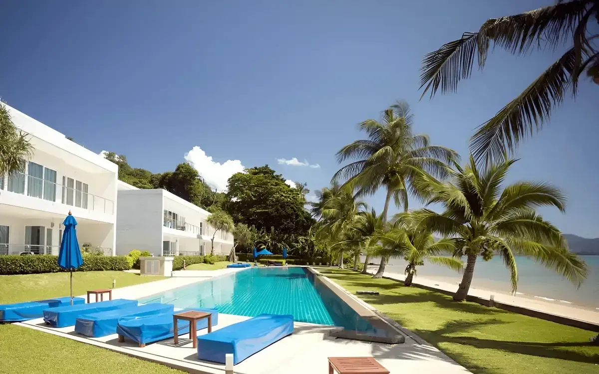 Beachfront swimming pool with sun loungers, palm trees, and sea views at The Waterside Condo.